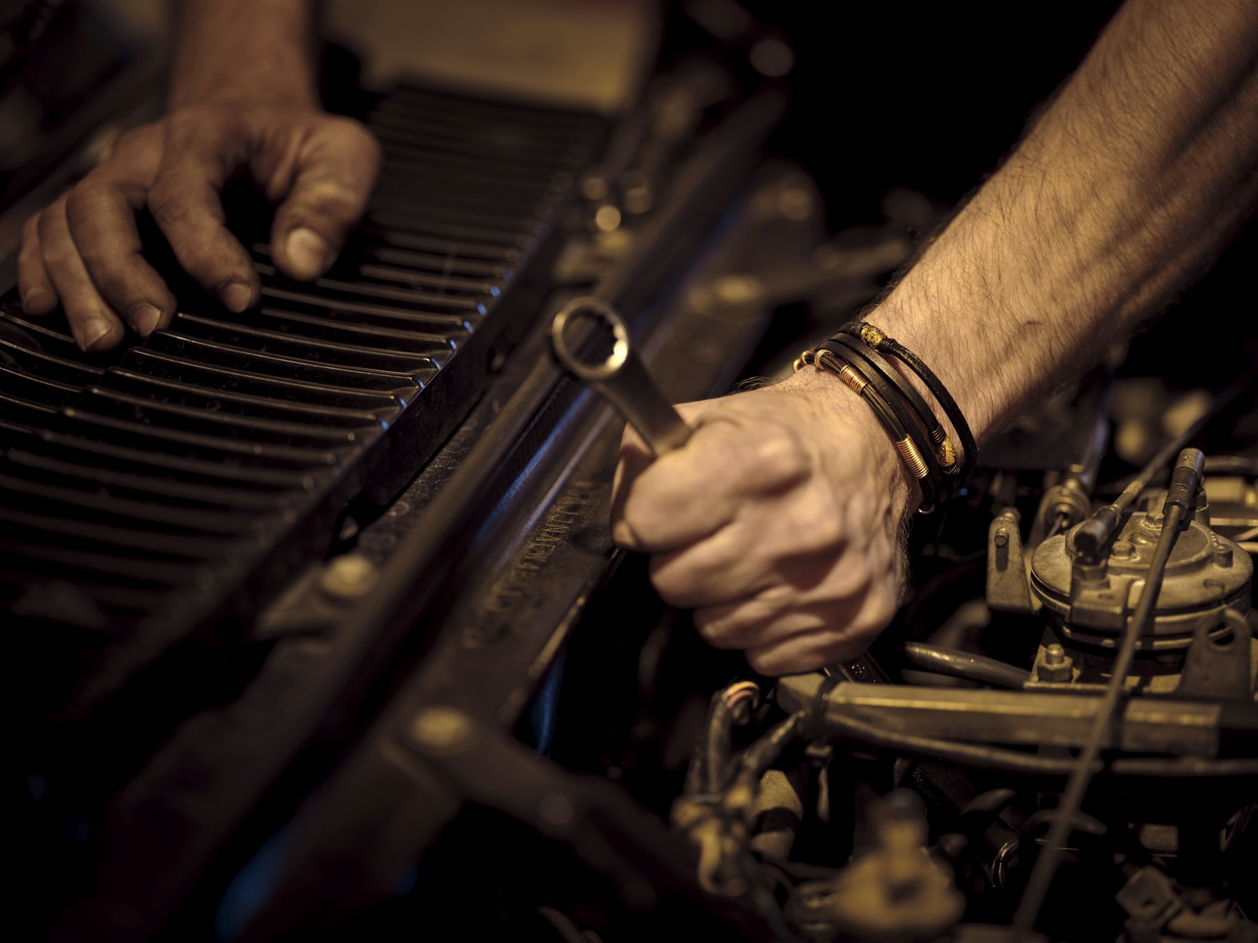 Hands using a socket wrench in an open engine bay