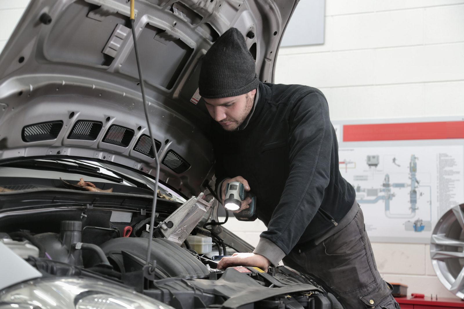 Two technicians working beneath a car raised on a hoist